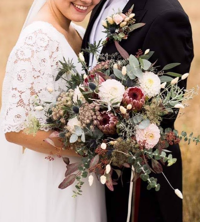 Bride and groom holding a beautiful bridal bouquet, featuring elegant flowers, in a romantic wedding setting
